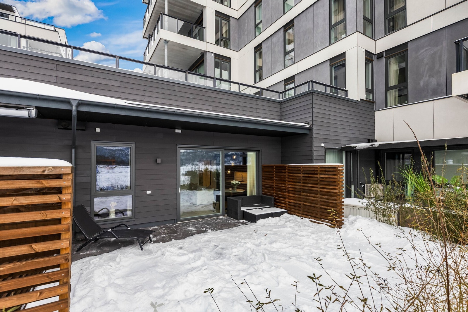 Terrassen er flislagt og har levegger på begge sider som skjermer for innsyn og skaper en mer privat atmosfære Galleribilde