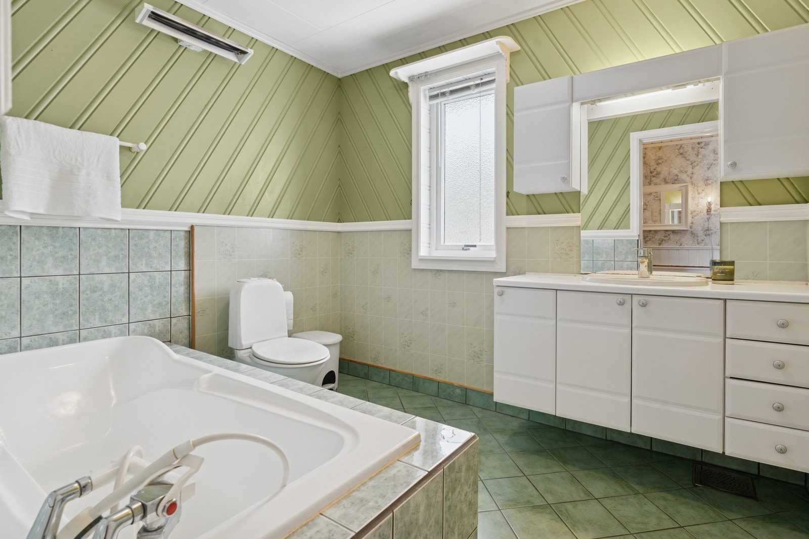 Bad i hovedetasjen med badekar, toalett og baderomsinnredning. Galleribilde