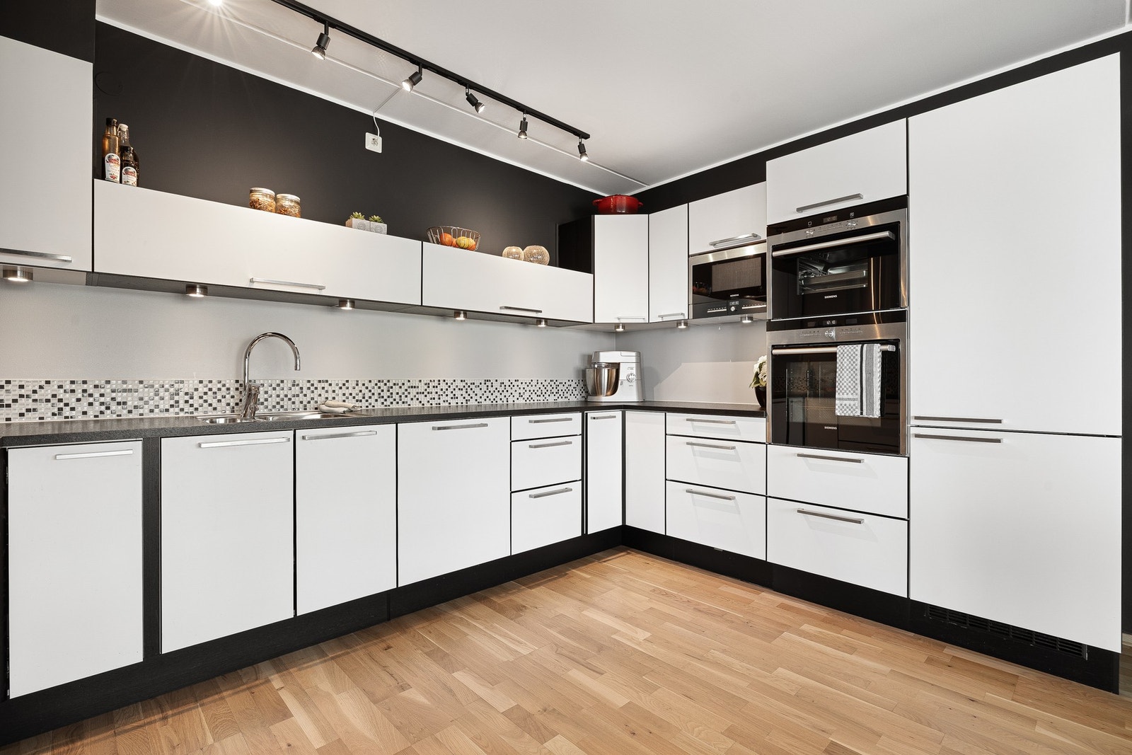 Stilrent kjøkken i sort og hvitt med integrerte hvitevarer. Galleribilde