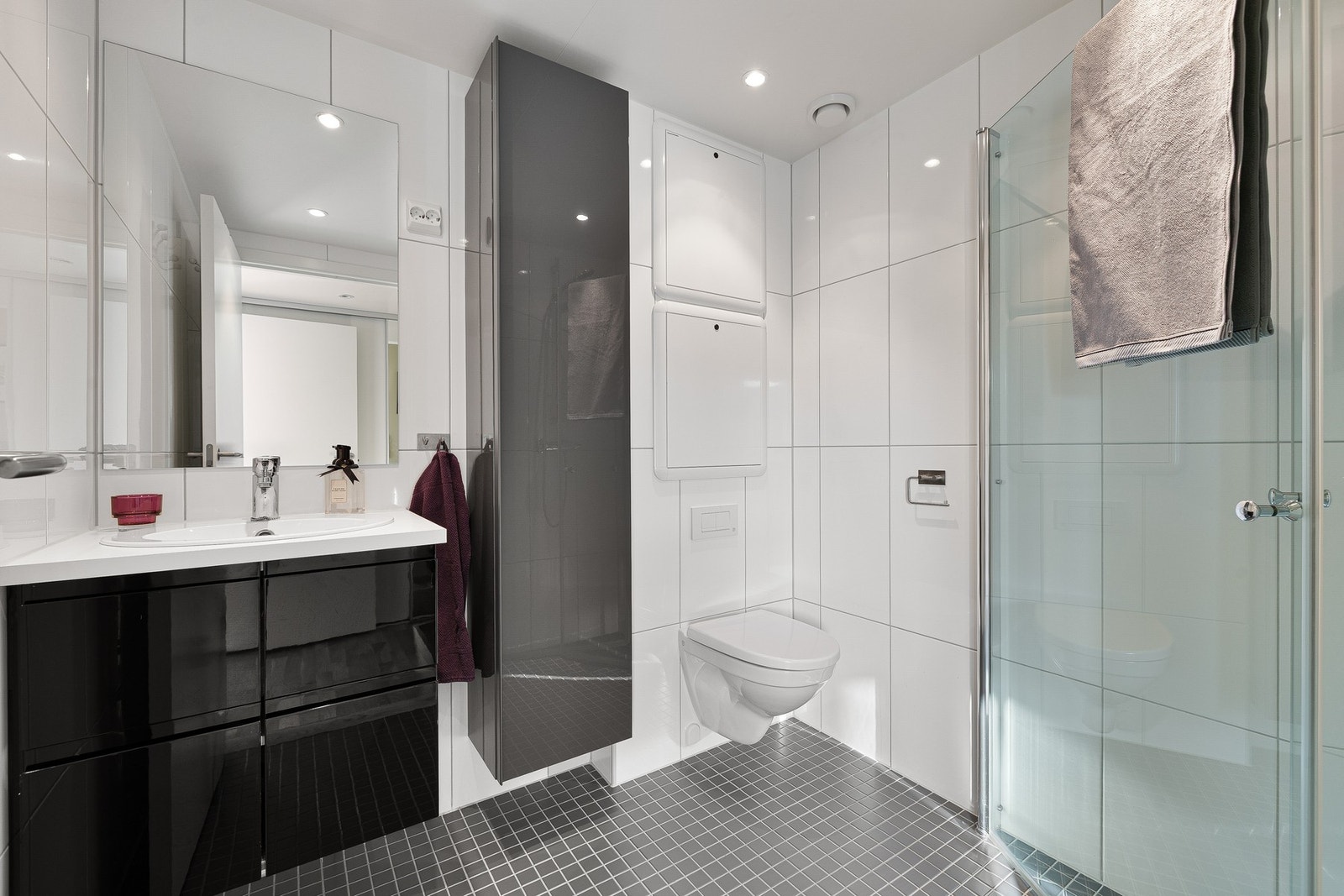 Flislagt bad med veggmontert servant, WC og 2stk dusjdører i glass. Galleribilde