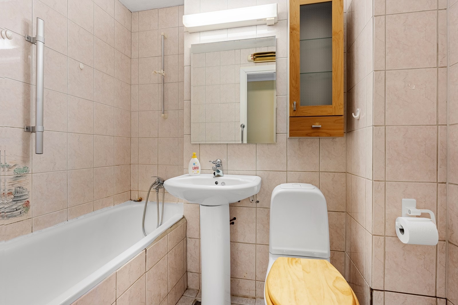 Badet er eldre og helfliset. Det er plass til et kombinert badekar/dusj, toalett, samt vask. Galleribilde