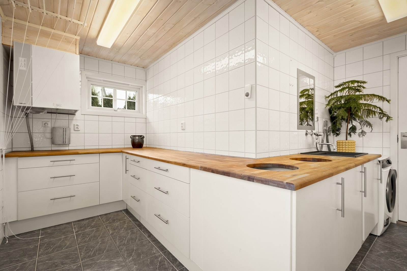 Romslig vaskerom med fliser, gulvvarme og god skap- og benkeplass. Galleribilde