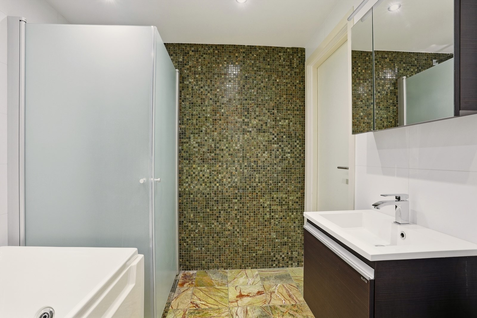 Badet er oppusset i 2008, står det i tilstandsrapporten. Rommet har innredning med nedfelt servant, badekar, dusjvegger/hjørne, opplegg for vaskemaskin og tørketrommel. Galleribilde