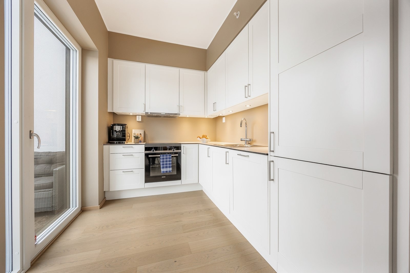 Innredningen har profilerte fronter og integrerte hvitevarer som platetopp, stekeovn og oppvaskmaskin Galleribilde