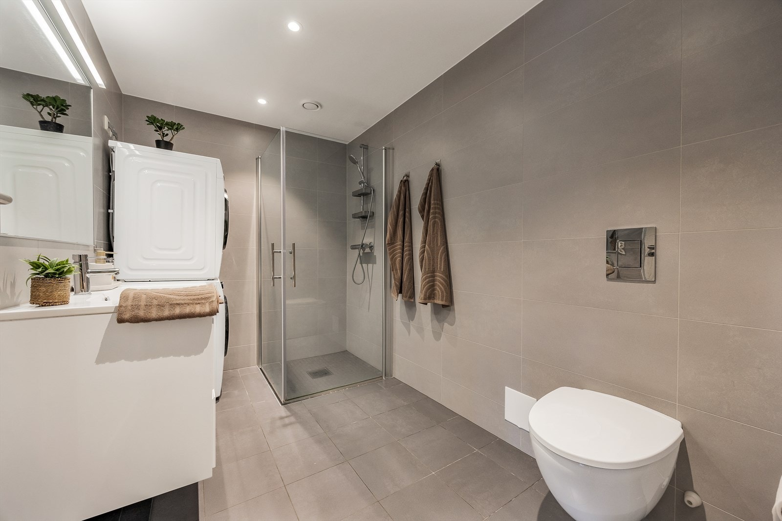 Badet er utstyrt med vegghengt toalett og dusjhjørne med innfellbare glassdører Galleribilde