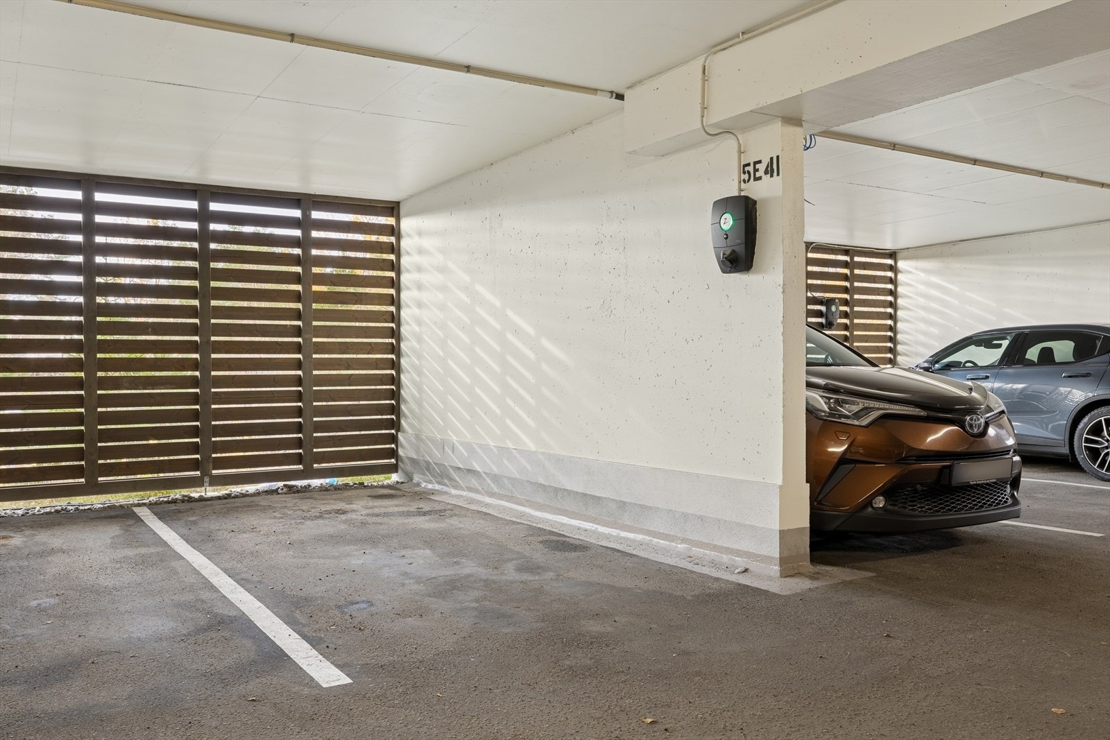 Parkeringsplass med el-bil lader og bod i felles garasjeanlegg. Galleribilde