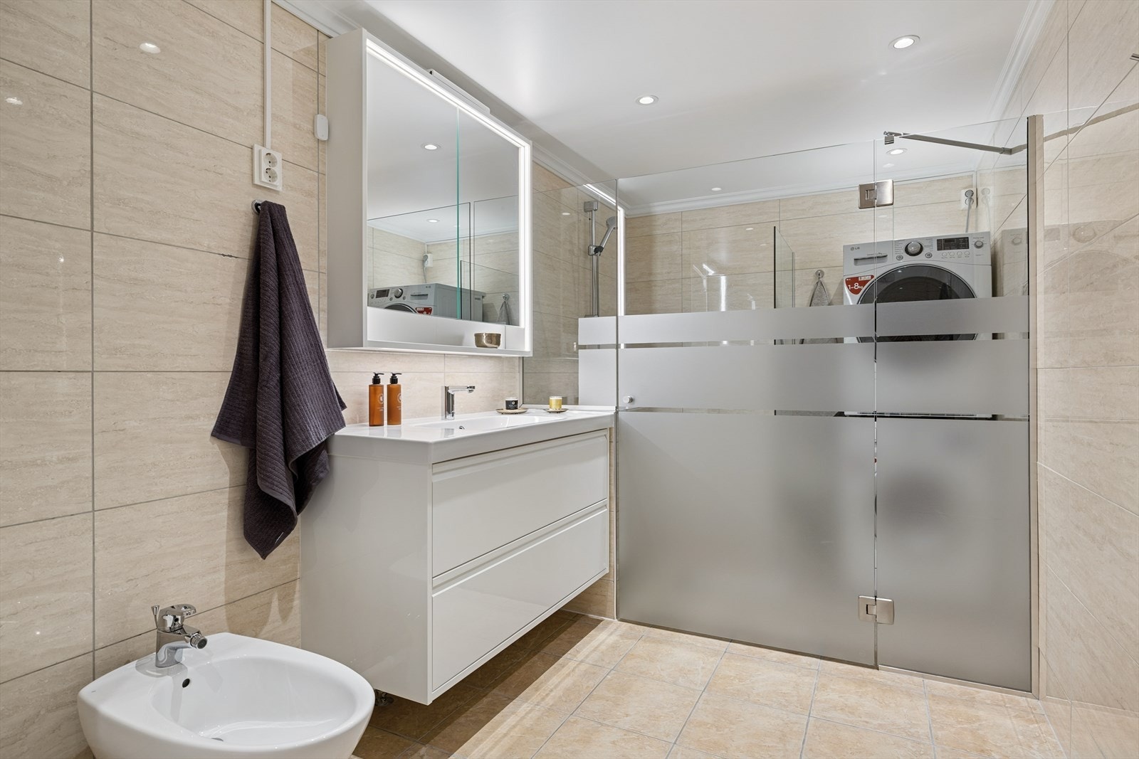 Badet er utstyrt med vegghengt toalett, bidé, dusj med glassdør, innredning med servant (2024) og speilskap. Det er opplegg for vaskemaskin og tørketrommel. Galleribilde