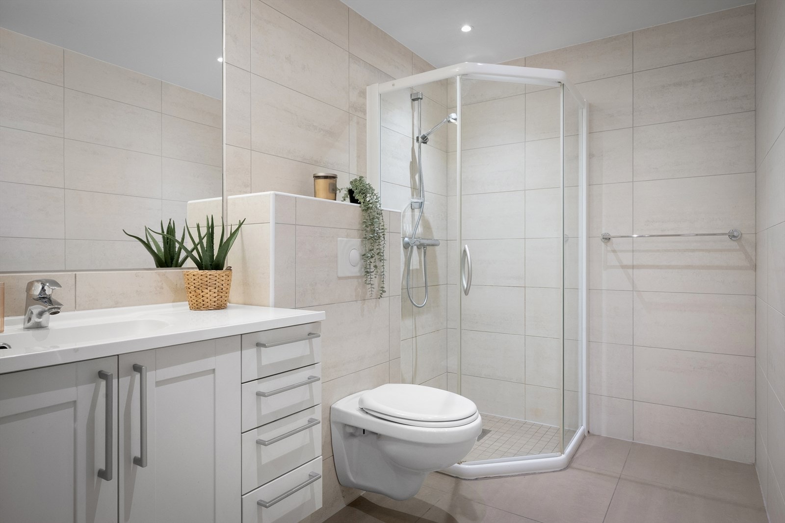 Bad/vaskerommet er helfliset og praktisk innredet med servant, vegghengt toalett, dusjhjørne og opplegg for vaskemaskin. Galleribilde