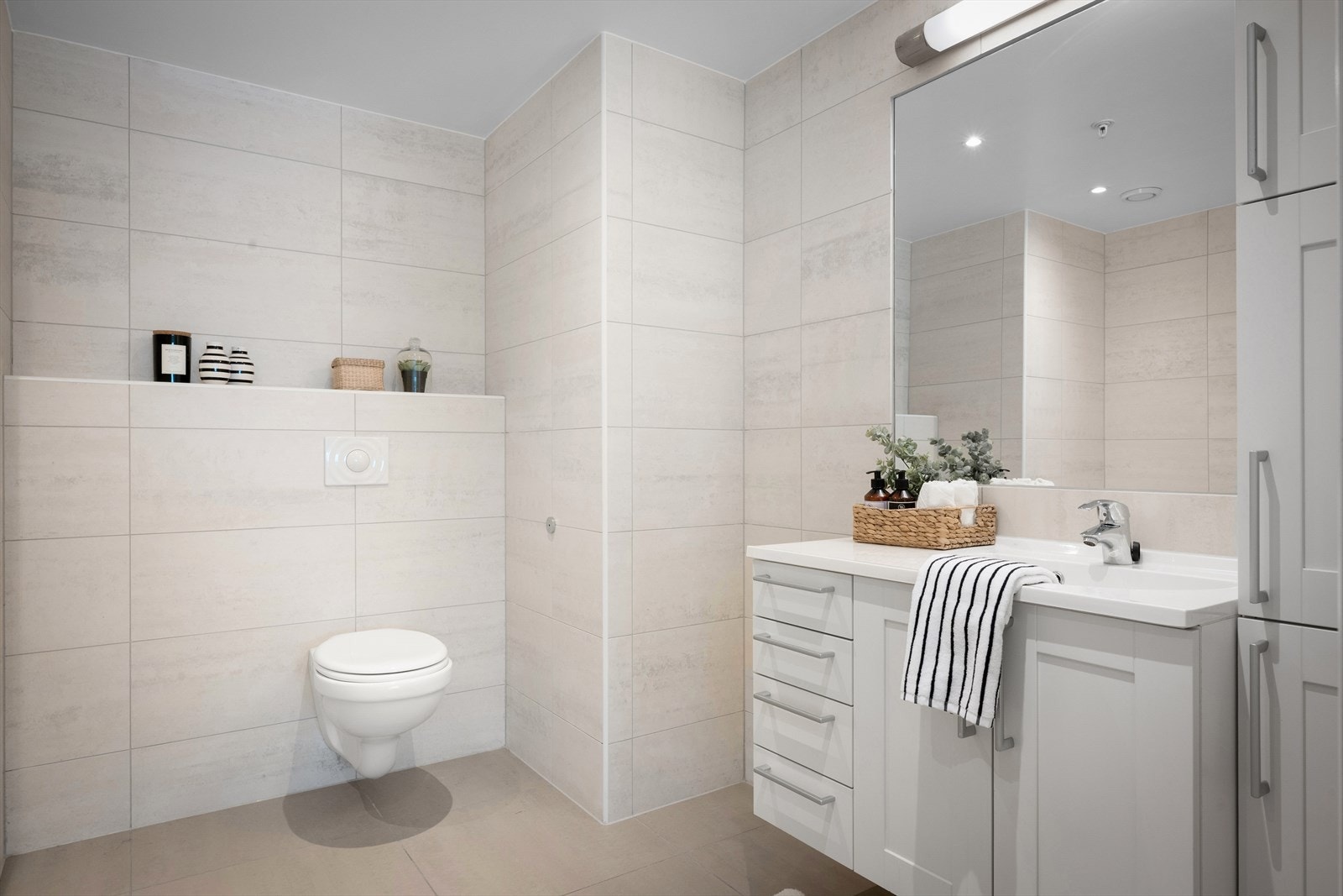 Badet er lekkert, helfliset og utstyrt med vannbåren gulvvarme, vegghengt toalett, servant og badekar. Galleribilde