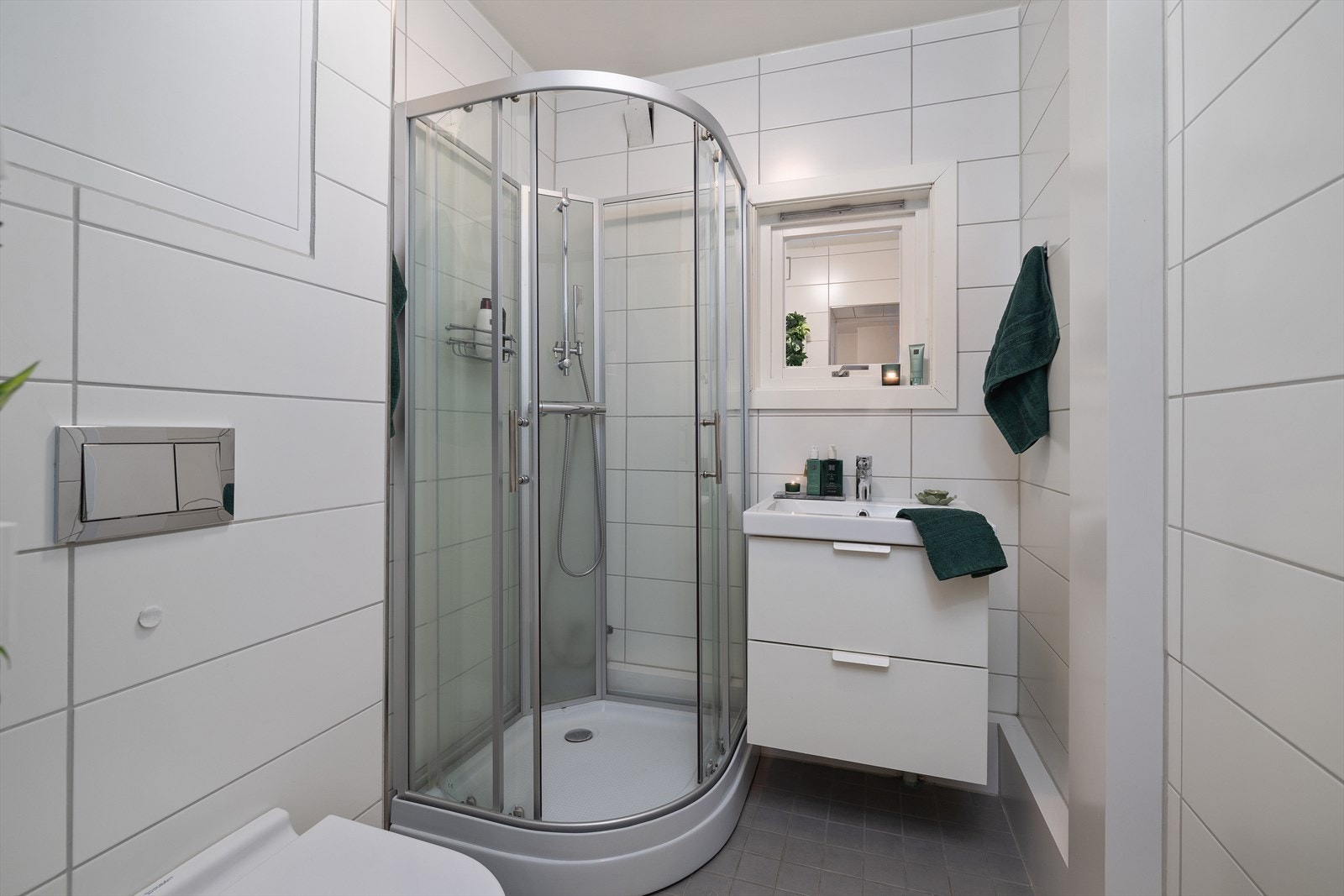 Flislagt bad med elektriske varmekabler i gulvet, dusjkabinett og vegghengt toalett. Galleribilde