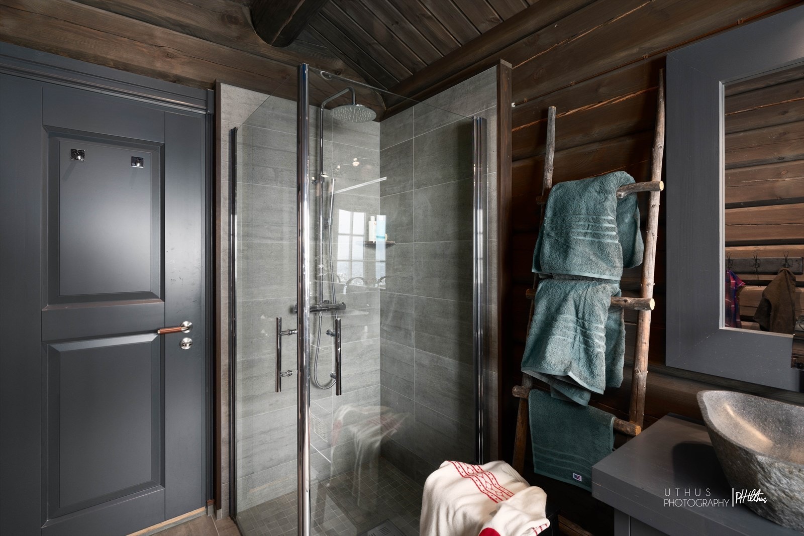 Bad 2 i 1.etasje har flislagte vegger i dusjsonen samt flislagt gulv, kombinert med laftede vegger og trepanel i tak Galleribilde