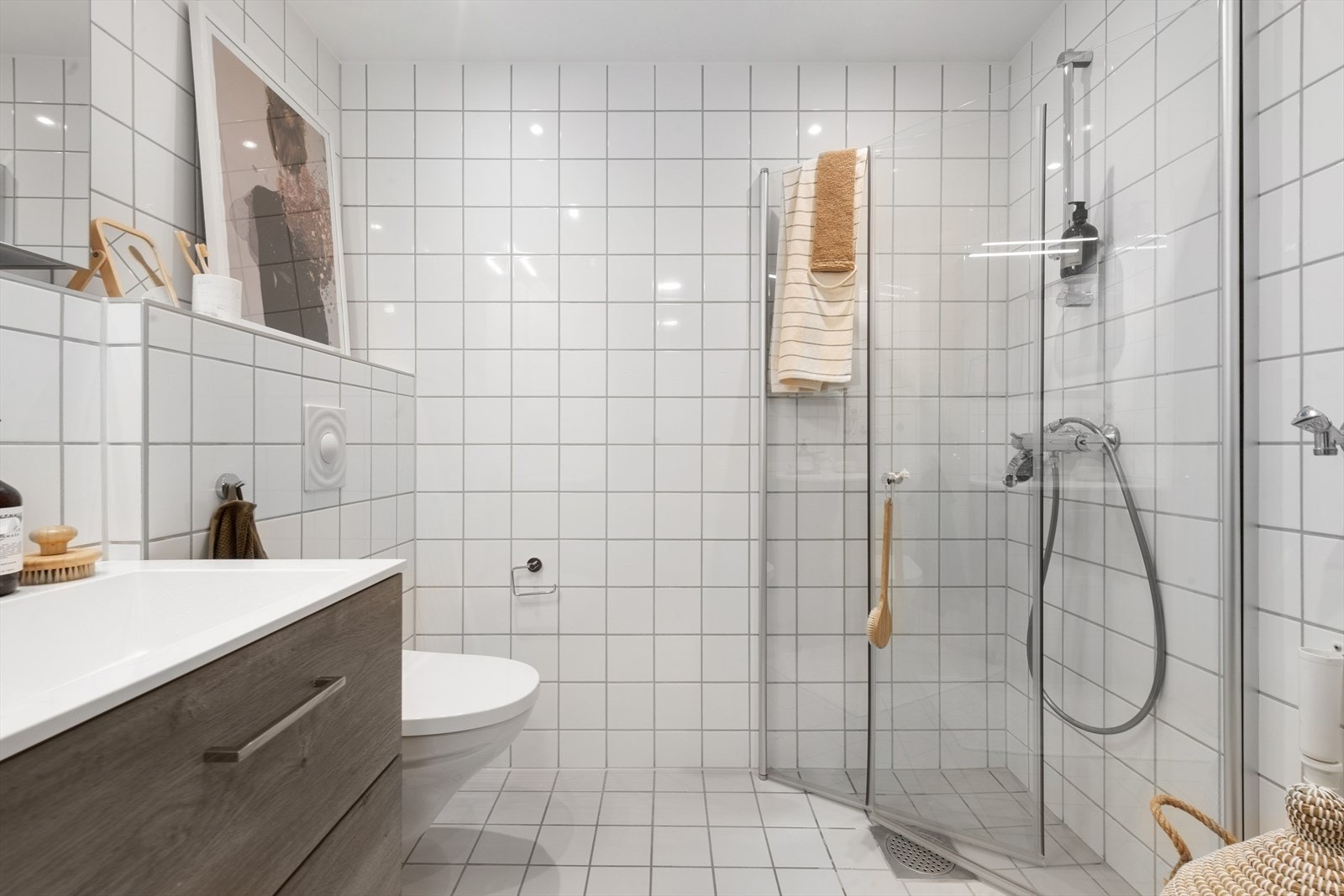 Lyst flislagt bad, med veggmontert toalett og helt ny kombinert vaskemaskin og tørketrommel. Galleribilde