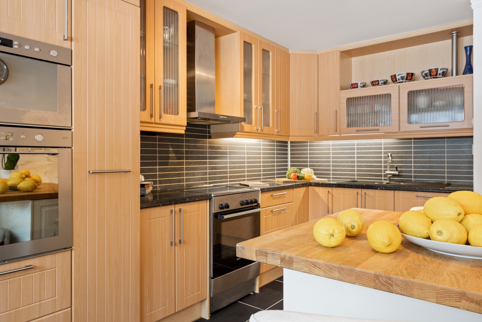 Kjøkkeninnredning med profilerte laminerte fronter og laminat benkeplater. Plater med flisimitat over benk. Galleribilde