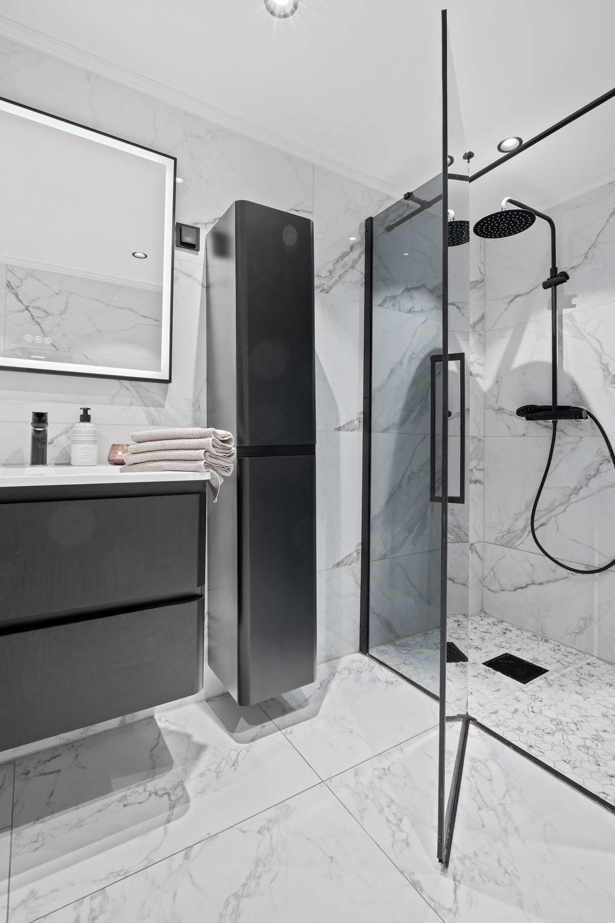 Innbydende bad med tidsriktig valg av materialer som sorte detaljer og downlights i tak. Galleribilde