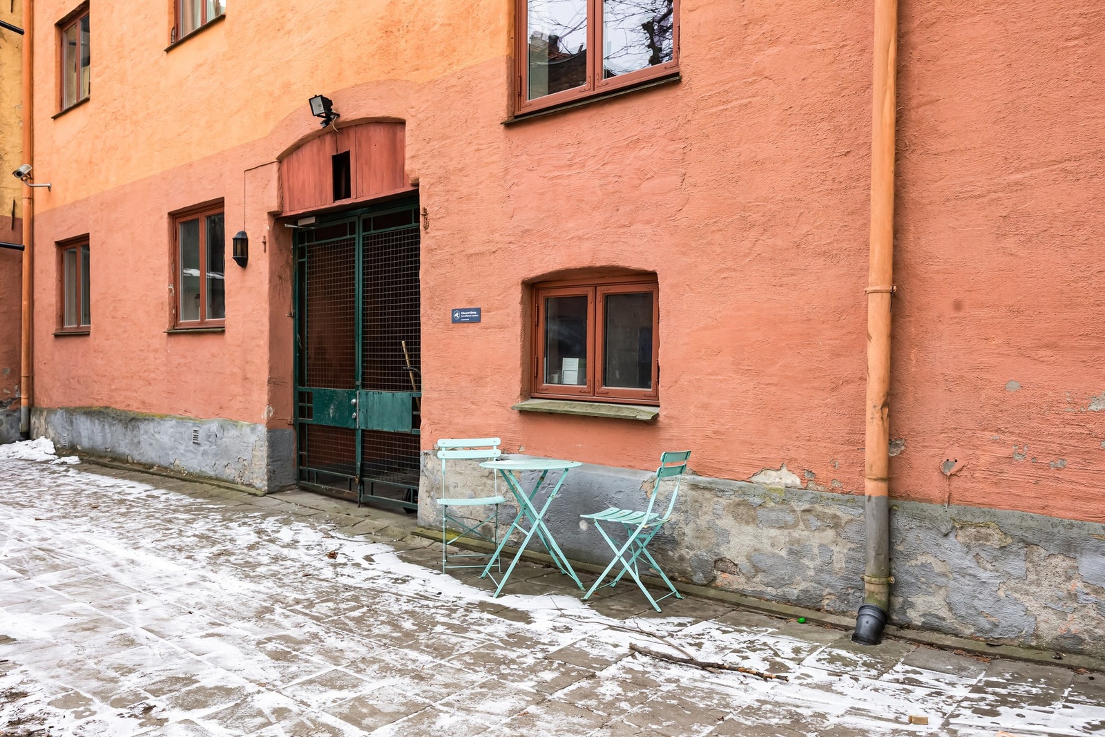 Bakgård belagt med betongheller, gressplen og diverse beplantinger samt sittegruppe. Galleribilde