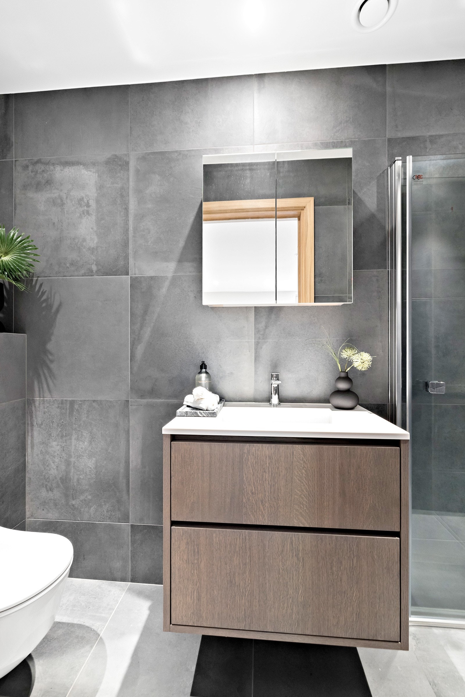 Badet er stilrent med vegg- og gulvfliser i ulike gråtoner. Galleribilde