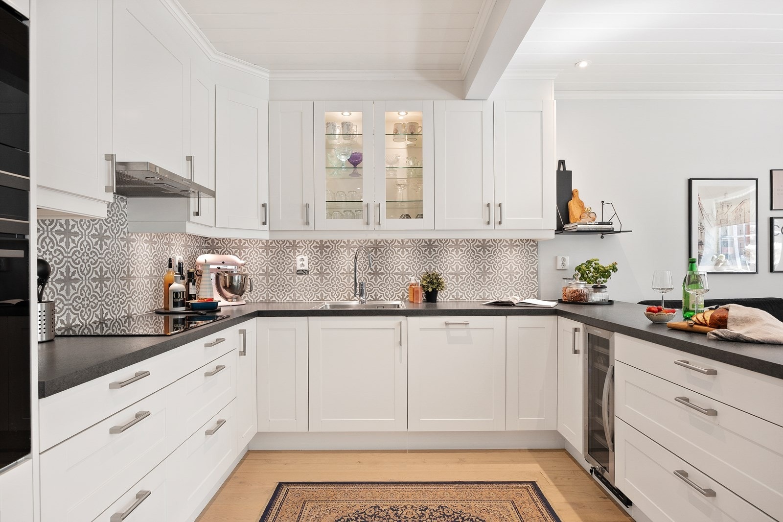 Kjøkkeninnredning med glatte fronter og takhøye overskap.
Benkeplate av laminat og oppvaskkum av stål med ett greps
blandebatteri. Galleribilde