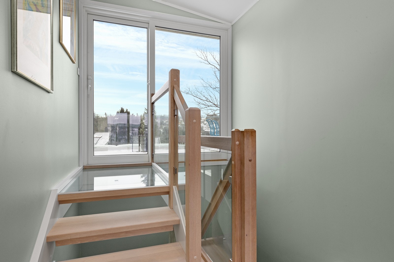 Enstavs hvit oljet innvendig eiketrapp med glassrekkverk og repo i glass leder videre ut til en skjermet og østvendt terrasse. Galleribilde
