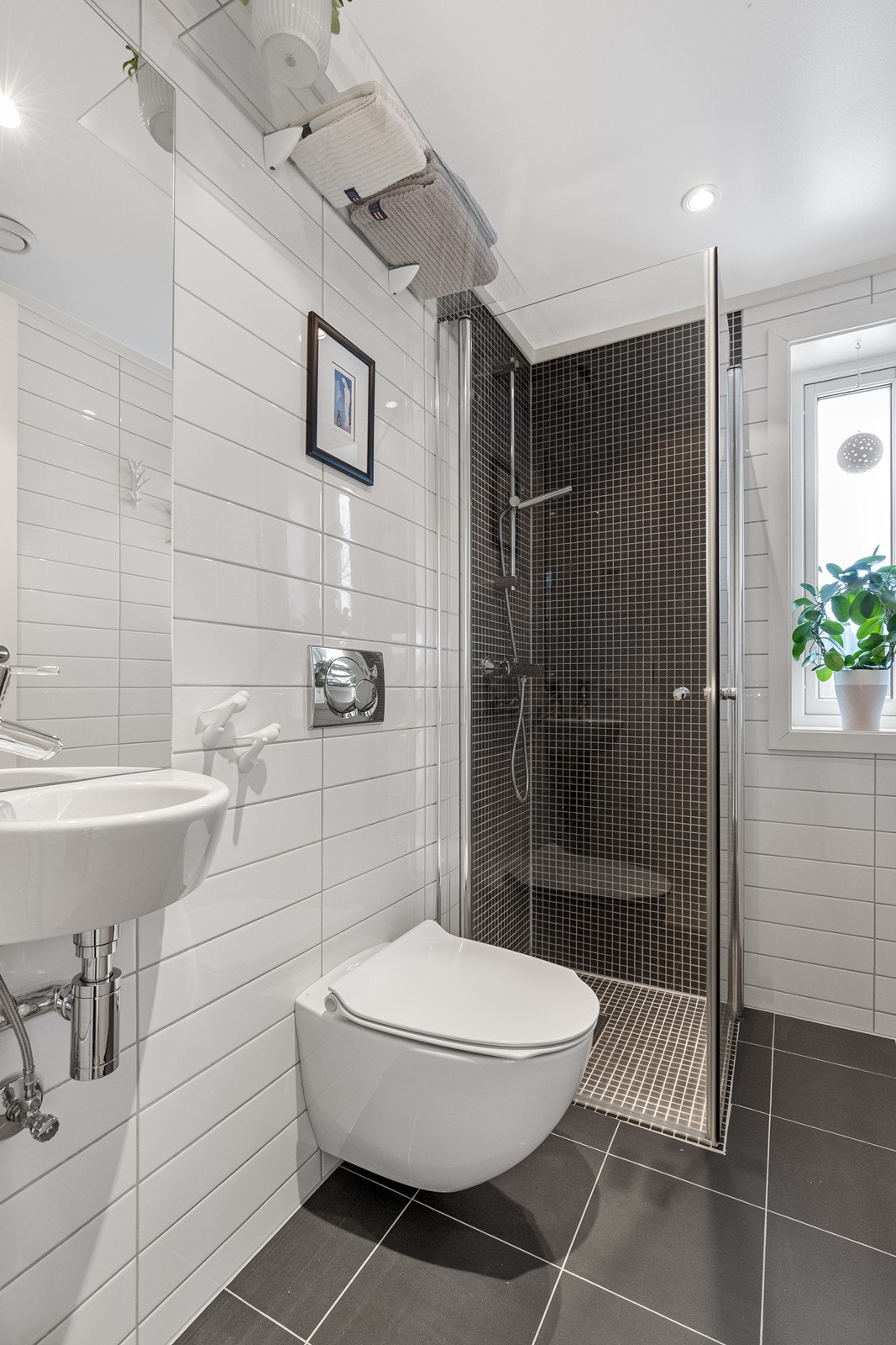 Flislagt toalettrom som er innredet til bad med vegghengt toalett og dusjhjørne. Galleribilde