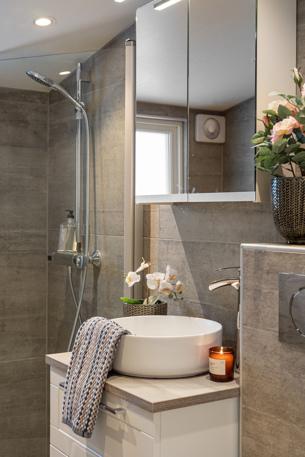 Baderommet har flislagt gulv og vegger, og er innredet med servantskap med topp servant, veggskap med speildører og belysning over. Galleribilde