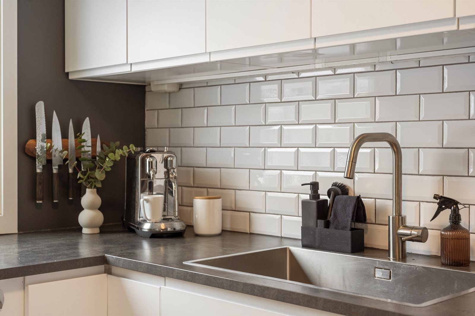 Det er fliser mellom benkeplate og overskap, samt laminat benkeplate med nedfelt oppvaskkum i rustfritt stål. Ettgreps svingbart blandingsbatteri i krom med dusjfunksjon.' Galleribilde