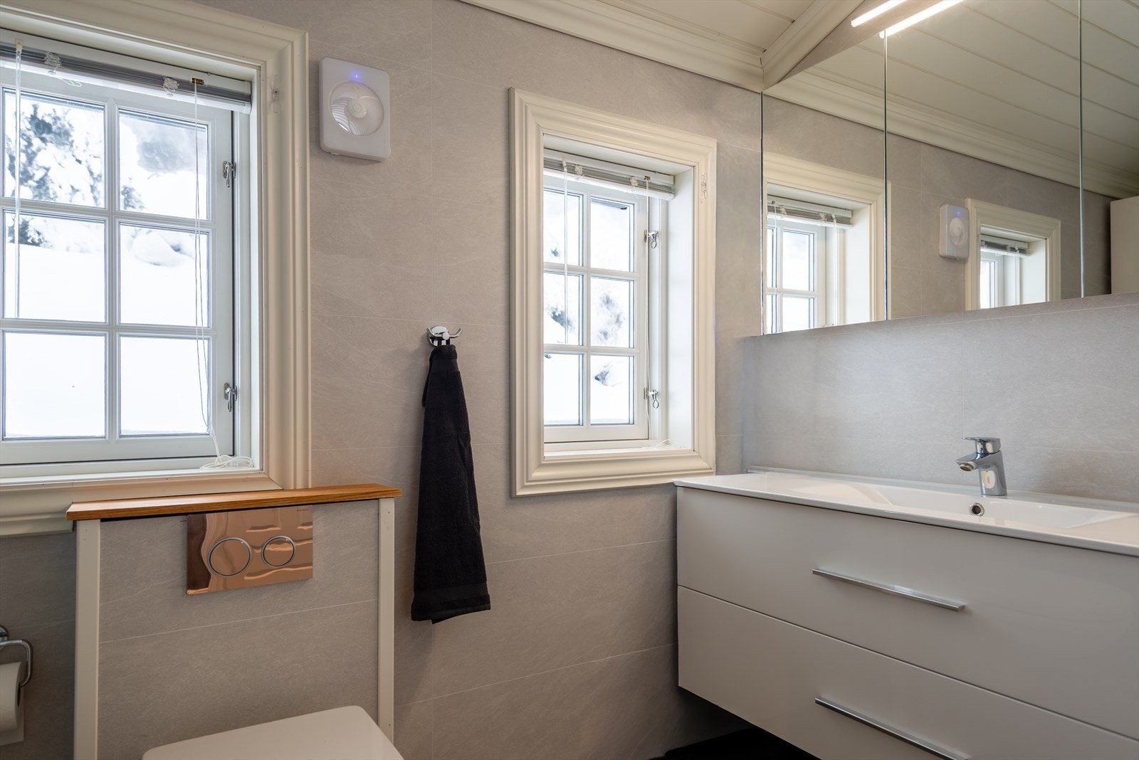 delikat baderom med vegghengt toalett. servant med skuffinnredning og godt med speilsskap. Galleribilde