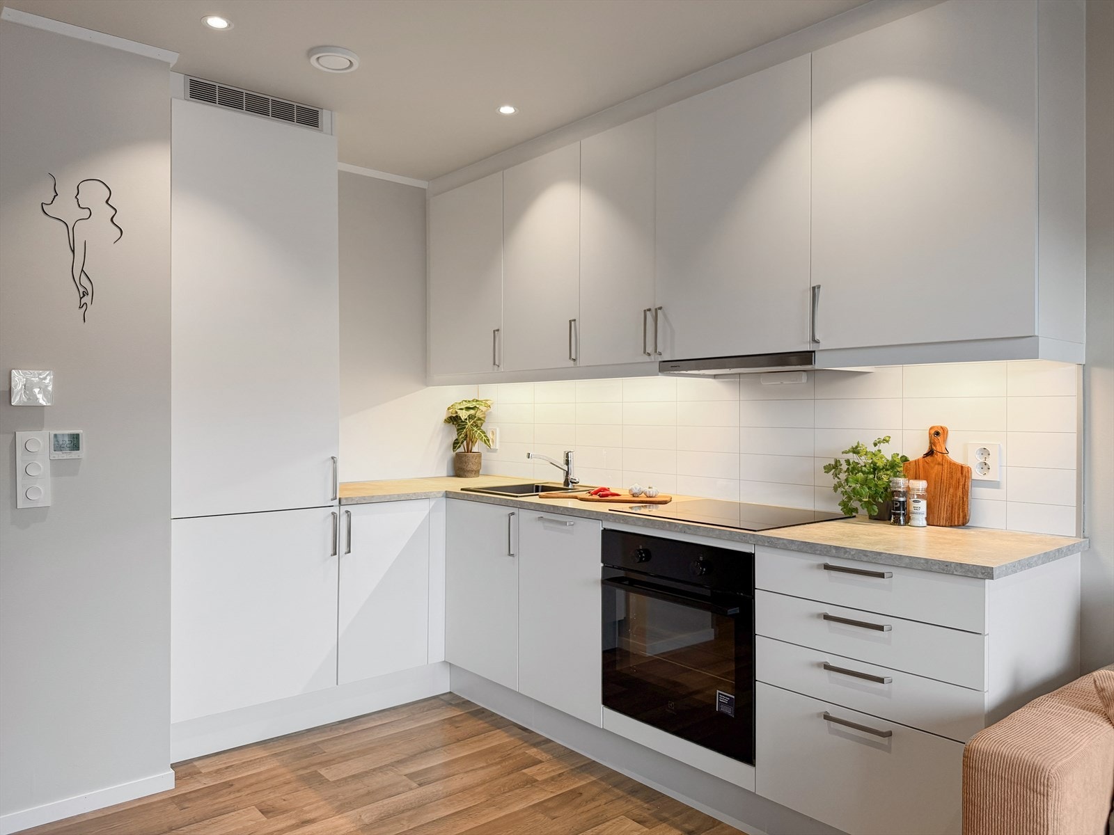 Kjøkkendelen er stilrein og har innreiing med lyse glatte frontar og integrerte kvitevarer som kjøl/fryseskap, oppvaskmaskin, platetopp og steikeovn Galleribilde