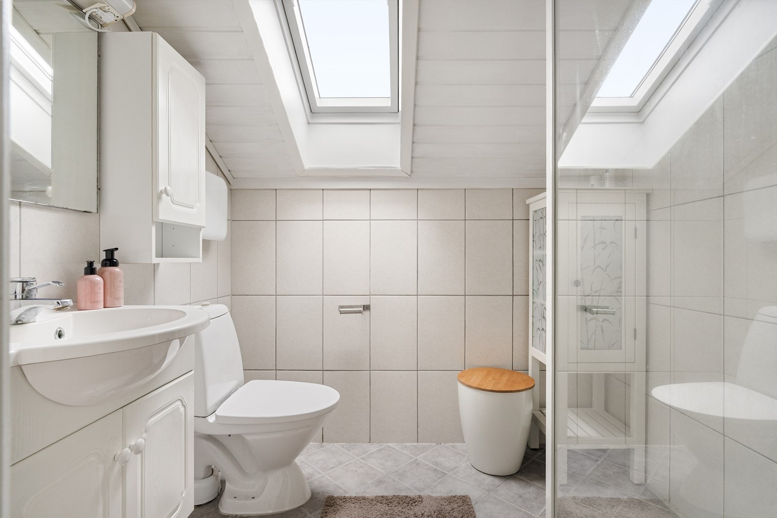 Flislagt bad med dusjnisje, toalett og en lys innredning med god plass til baderomsartikler. Galleribilde