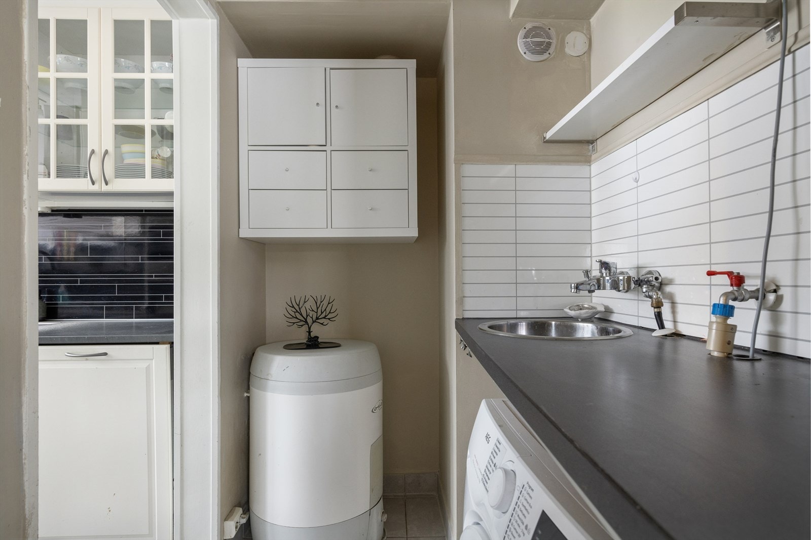 Vaskerom - Rommet har flislagt gulv og sokkelflis på vegg, benkeplate med utslagsvask og opplegg til vaskemaskin. Galleribilde