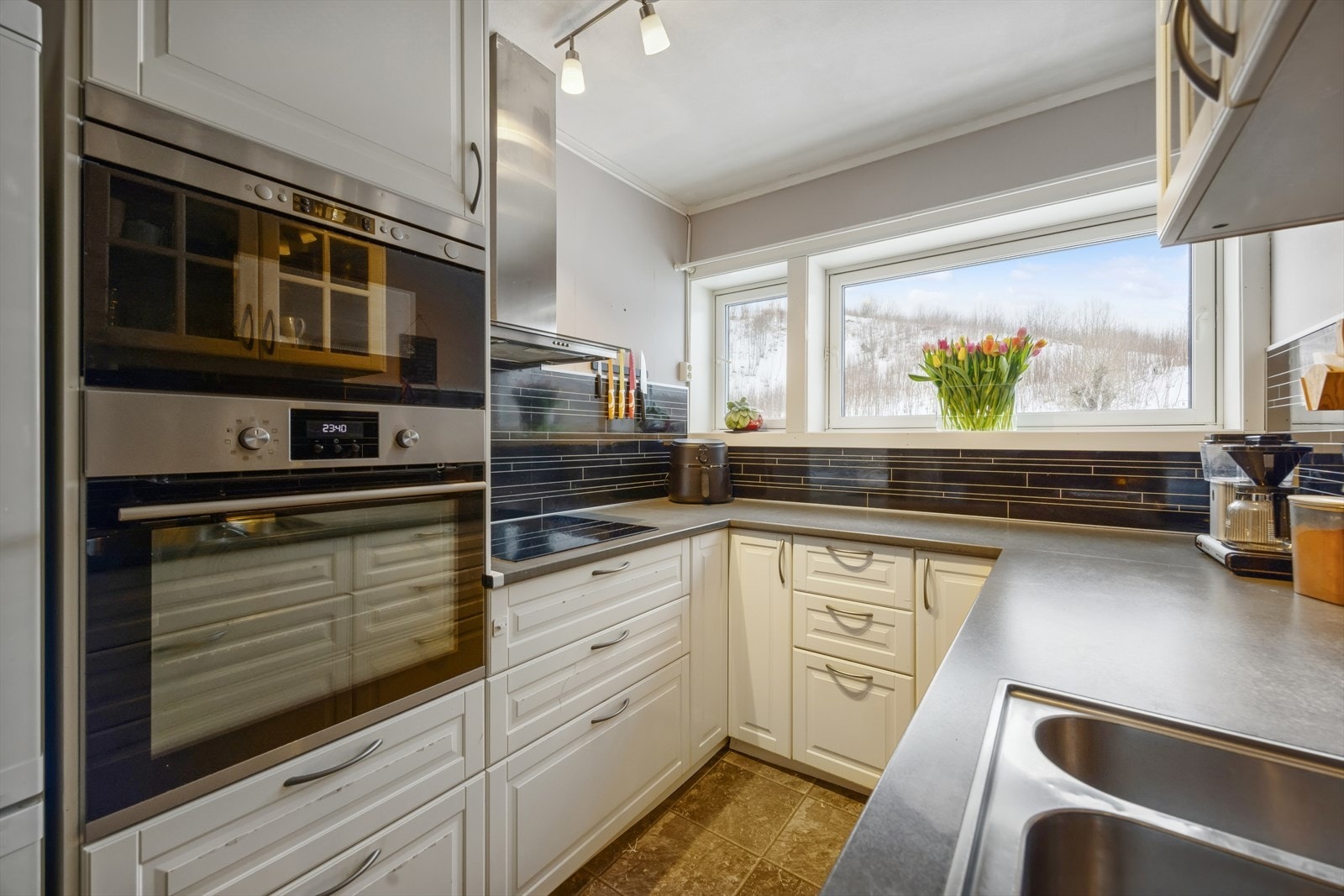 Kjøkken med plater på vegg over benkeplate. Rikelig med skap- og benkeplass. Galleribilde