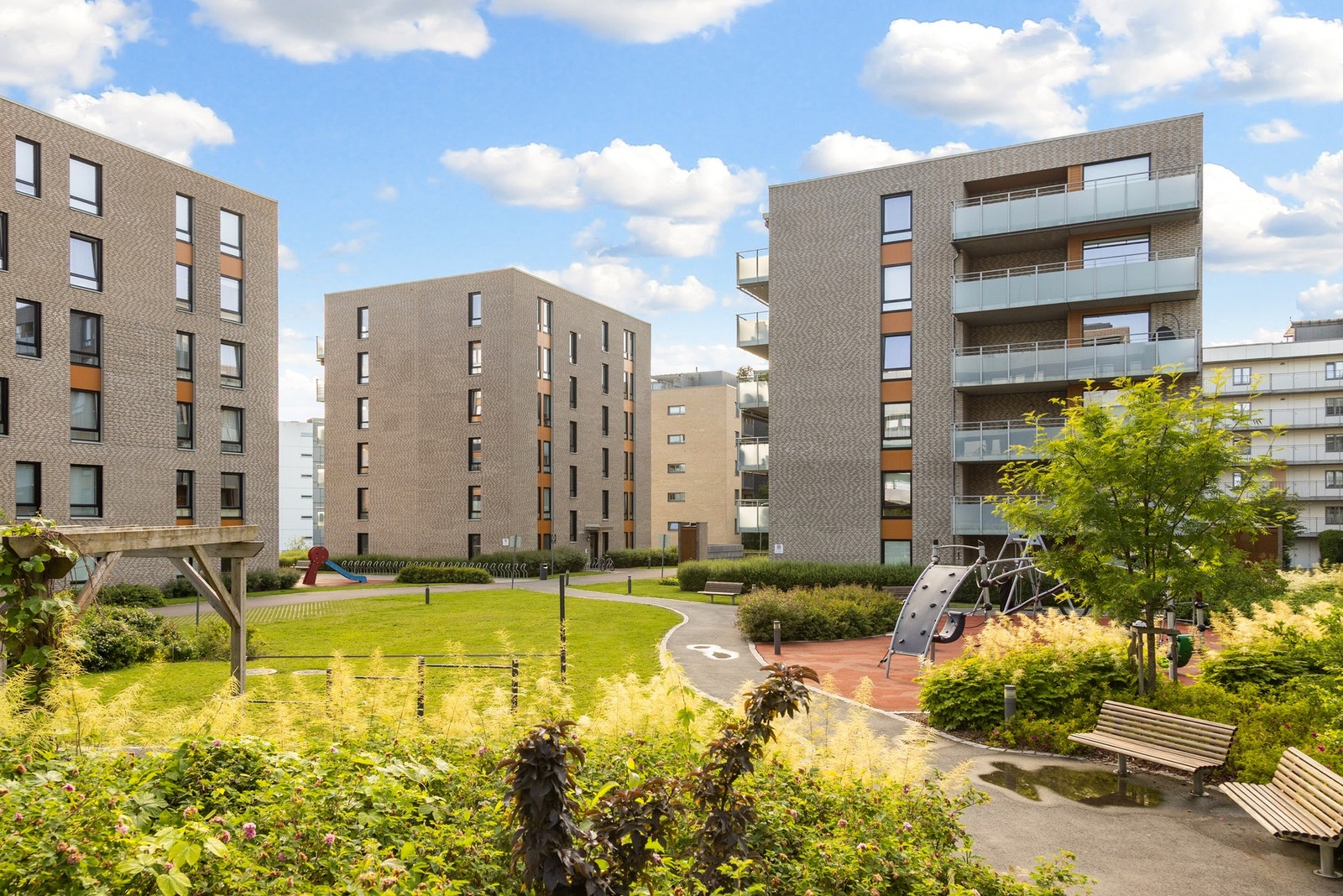 En idyllisk og rolig bakgård med plen, beplantning og lekeapparater for barna. Galleribilde
