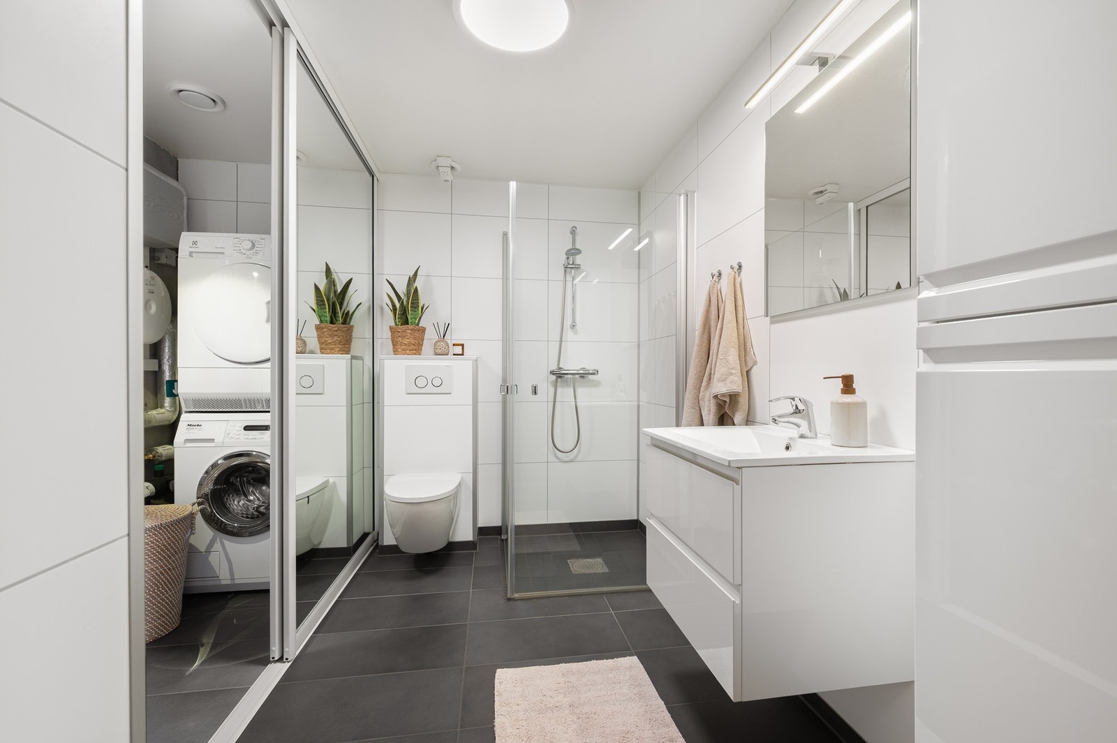 I kjeller er det et moderne bad, i kombinasjon med vaskerom. En fin og praktisk løsning, som skjuler vaskerom og teknisk rom. Galleribilde