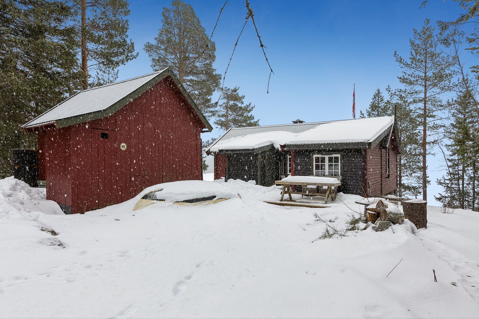 Fasaden presentert sammen med et innbydende uteområde som gir et godt førsteinntrykk av hytta. Galleribilde