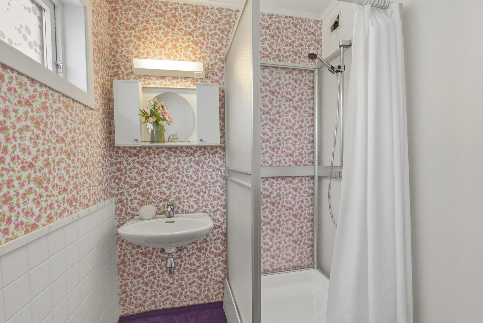 Bad med tapet/belegg og fliser på veggene. Innredning med servant og dusjkabinett. Galleribilde