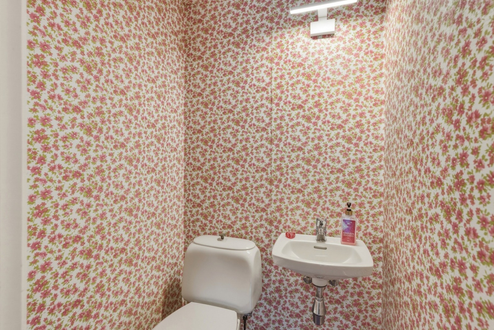 Toalettrom med gulvstående toalett og vegghengt servant. Galleribilde