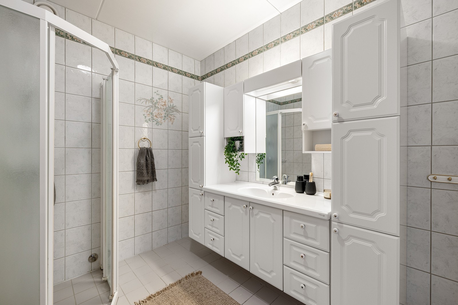 Bad med fliser på vegger og gulv med varmekabler. Dusjhjørne og skaper. Galleribilde