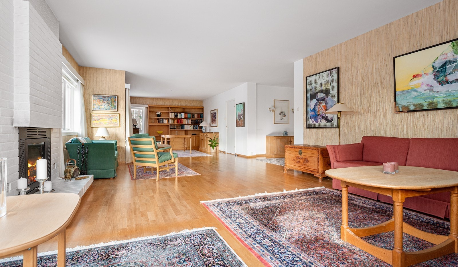 Lys og trivelig stue med peis og store vinduer mot syd og vest - spisestuen med bokhylle sees i bakkant (dør til kjøkkenet til høyre for spisestuen) Galleribilde