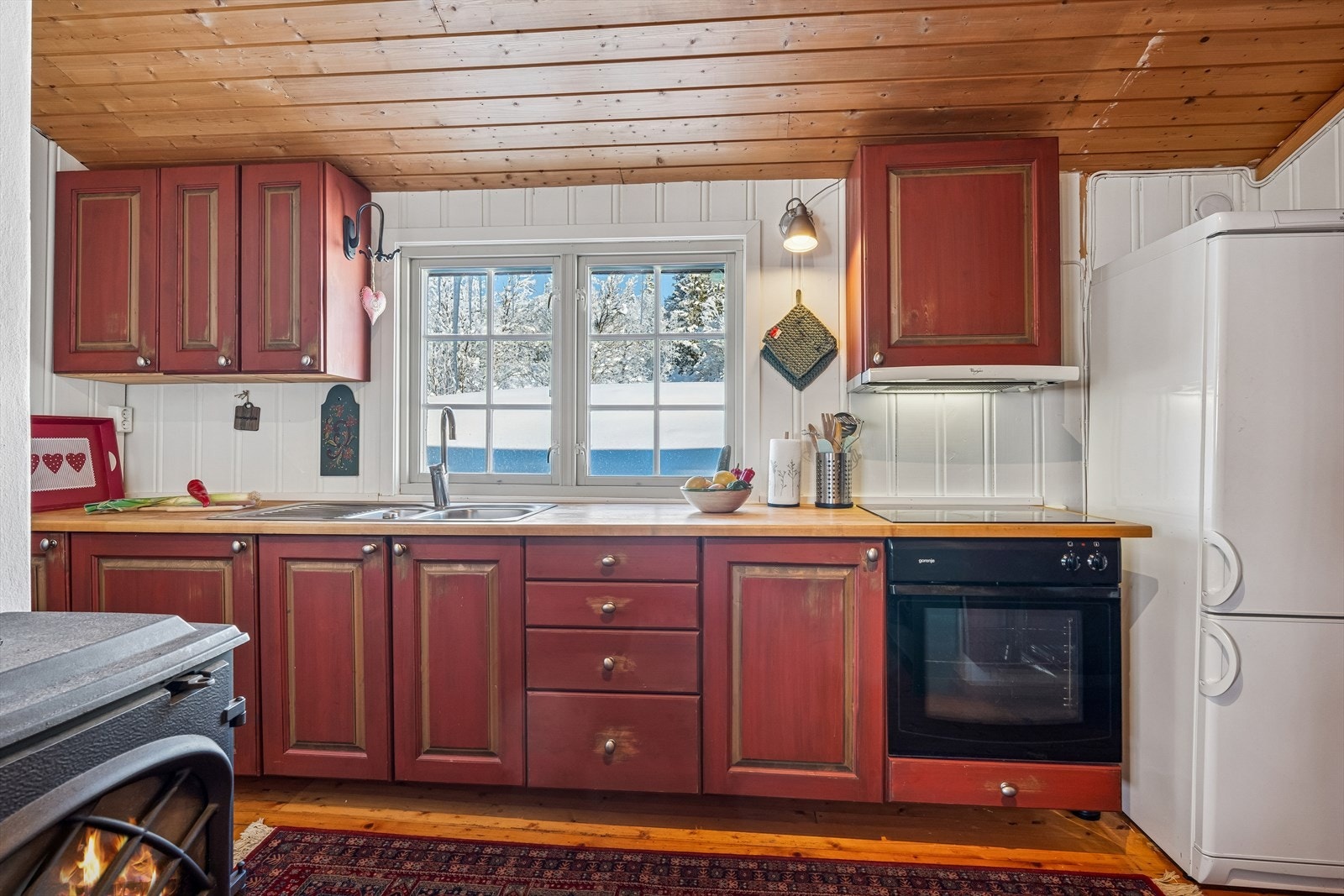 Integrerte hvitevarer med komfyr, ventilator og koketopp, samt frittstående kjøleskap. Galleribilde