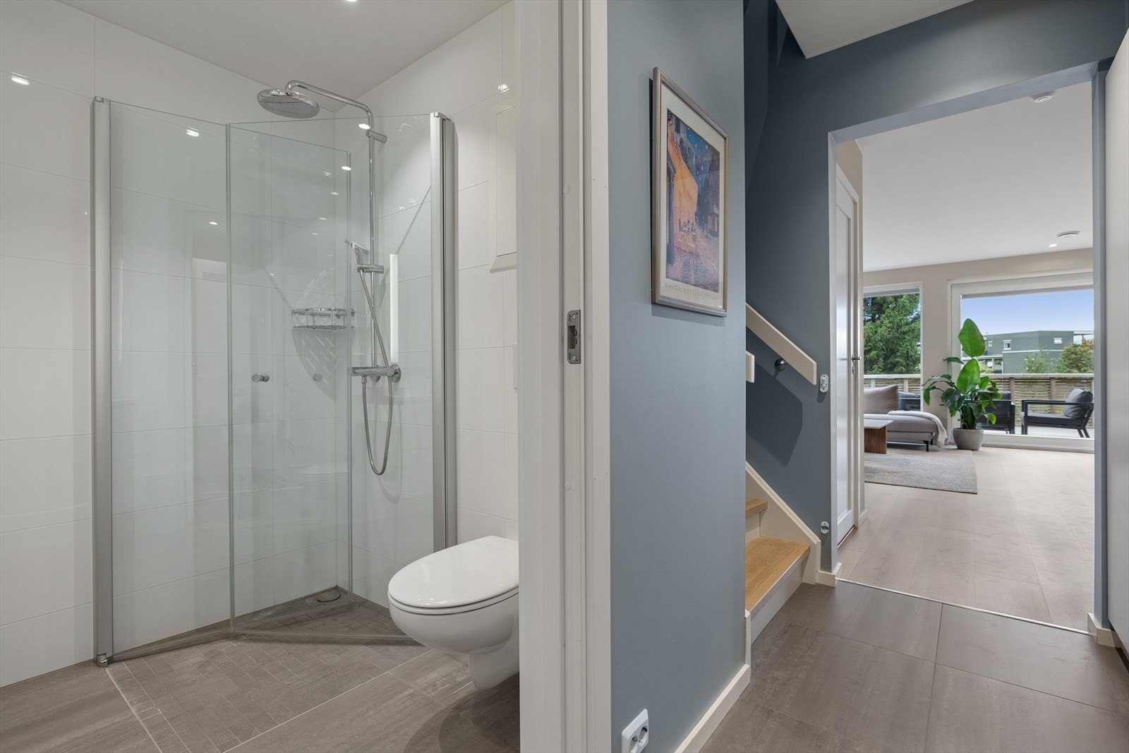 Baderommet er utstyrt med veggmontert toalett og dusjhjørne med glassdører. Galleribilde