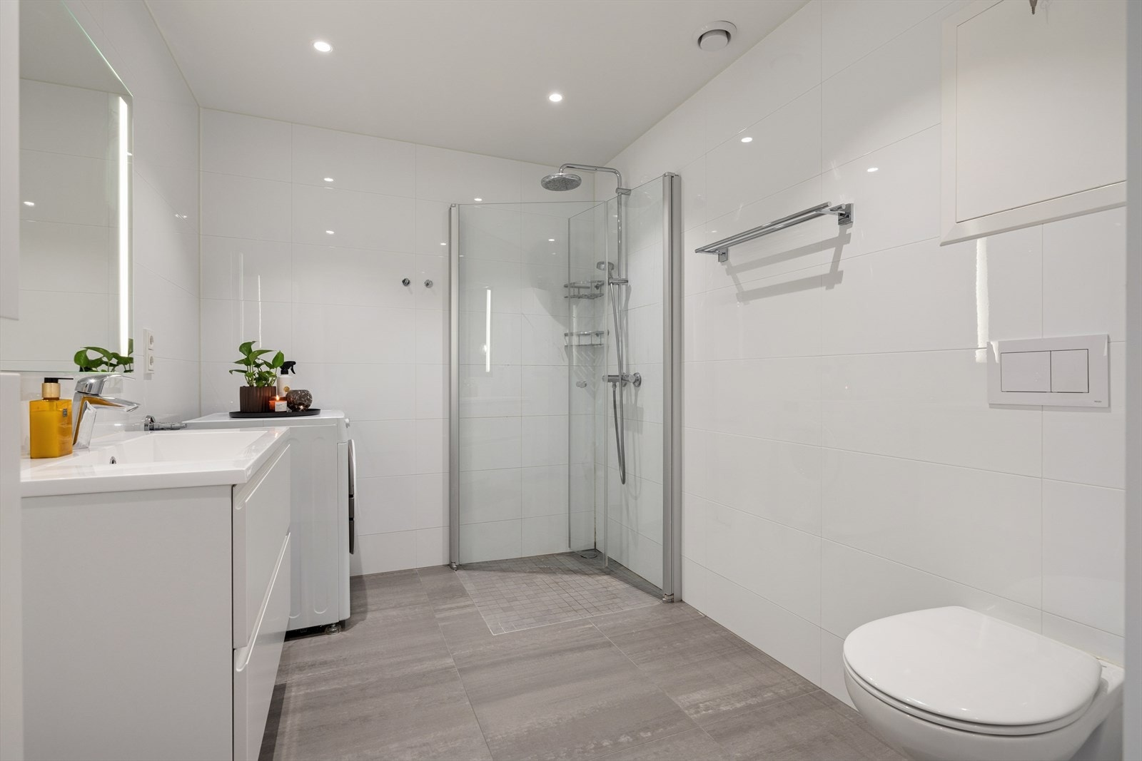 Baderommet består av vegghengt toalett, dusjhjørne med glassdører og innredning med nedfelt servant. Galleribilde