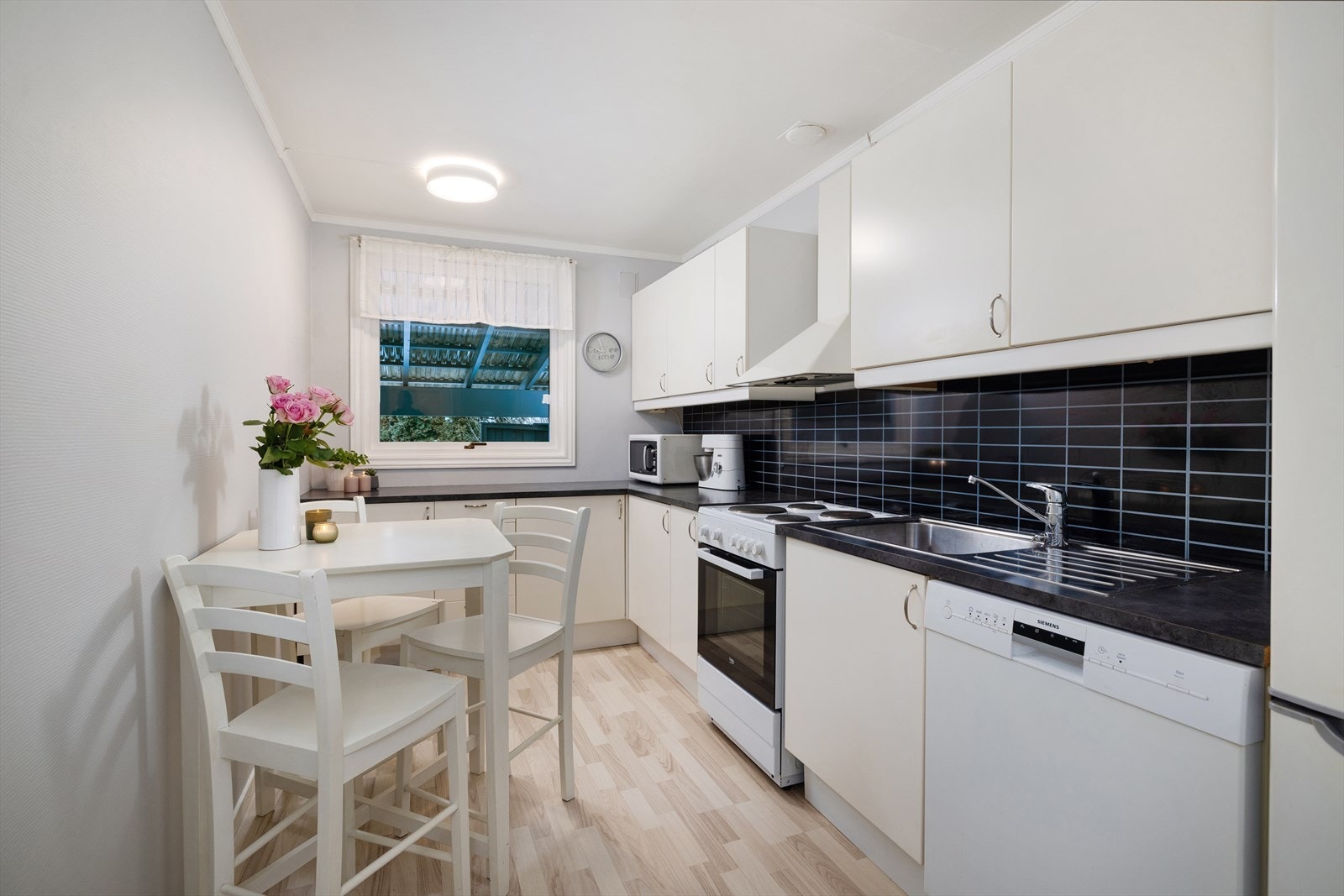 Praktisk kjøkken med glatte fronter, laminatbenkeplate og ventilator med avtrekk ut. Galleribilde