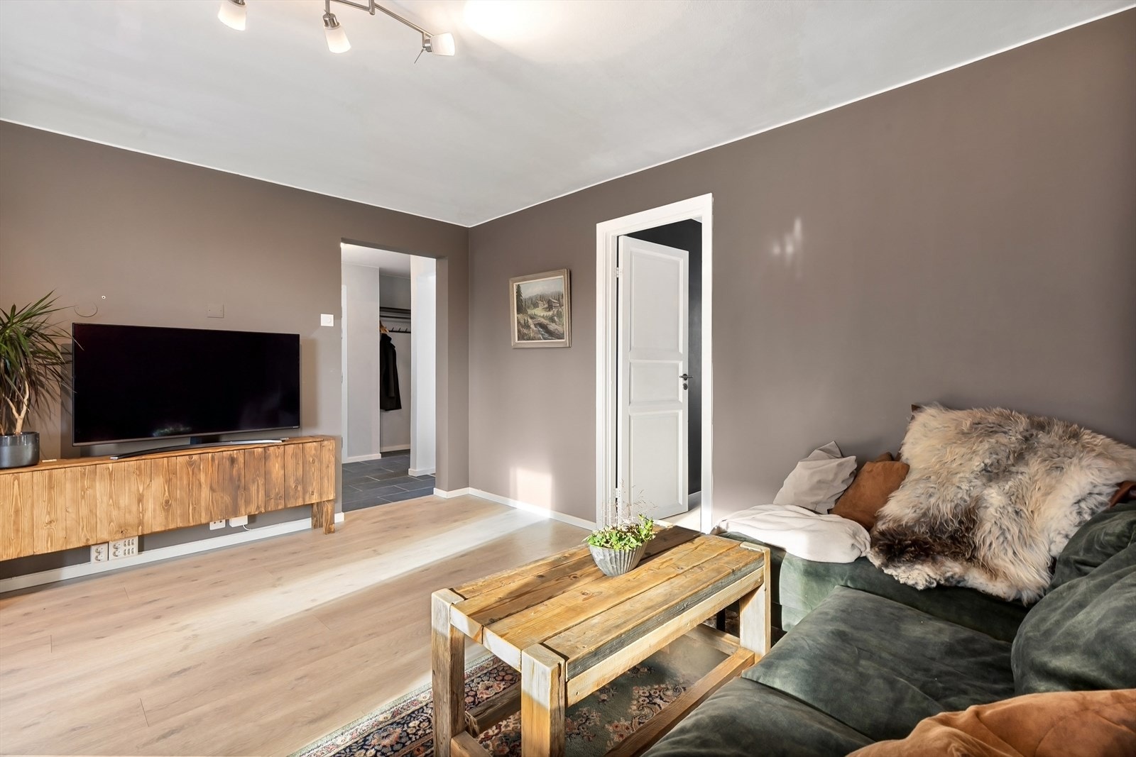 Stuen har enstavs laminatgulv og malte overflater i en brun, dempet farge. Galleribilde