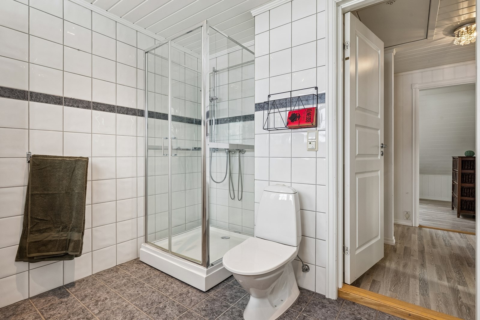 Badet er utstyrt med dusjkabinett med glassvegger og gulvmontert toalett. Galleribilde