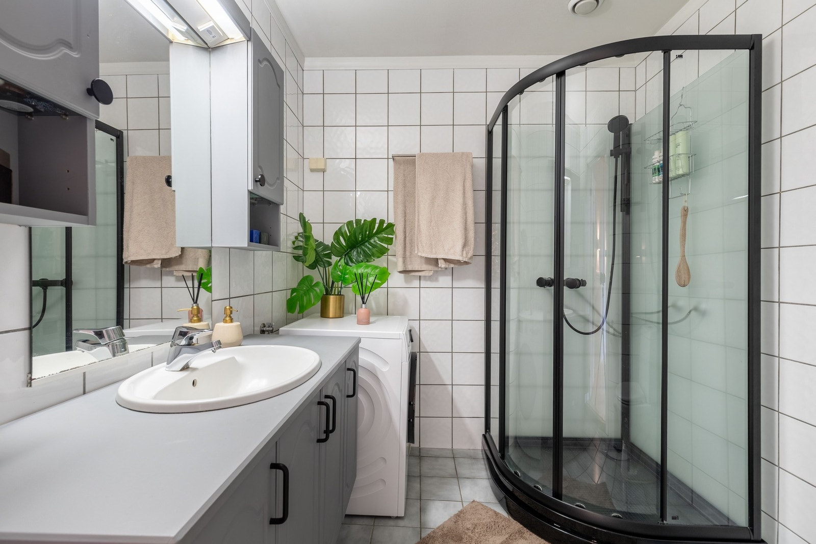Badet har grå fliser på gulv og hvite fliser på vegger. Galleribilde