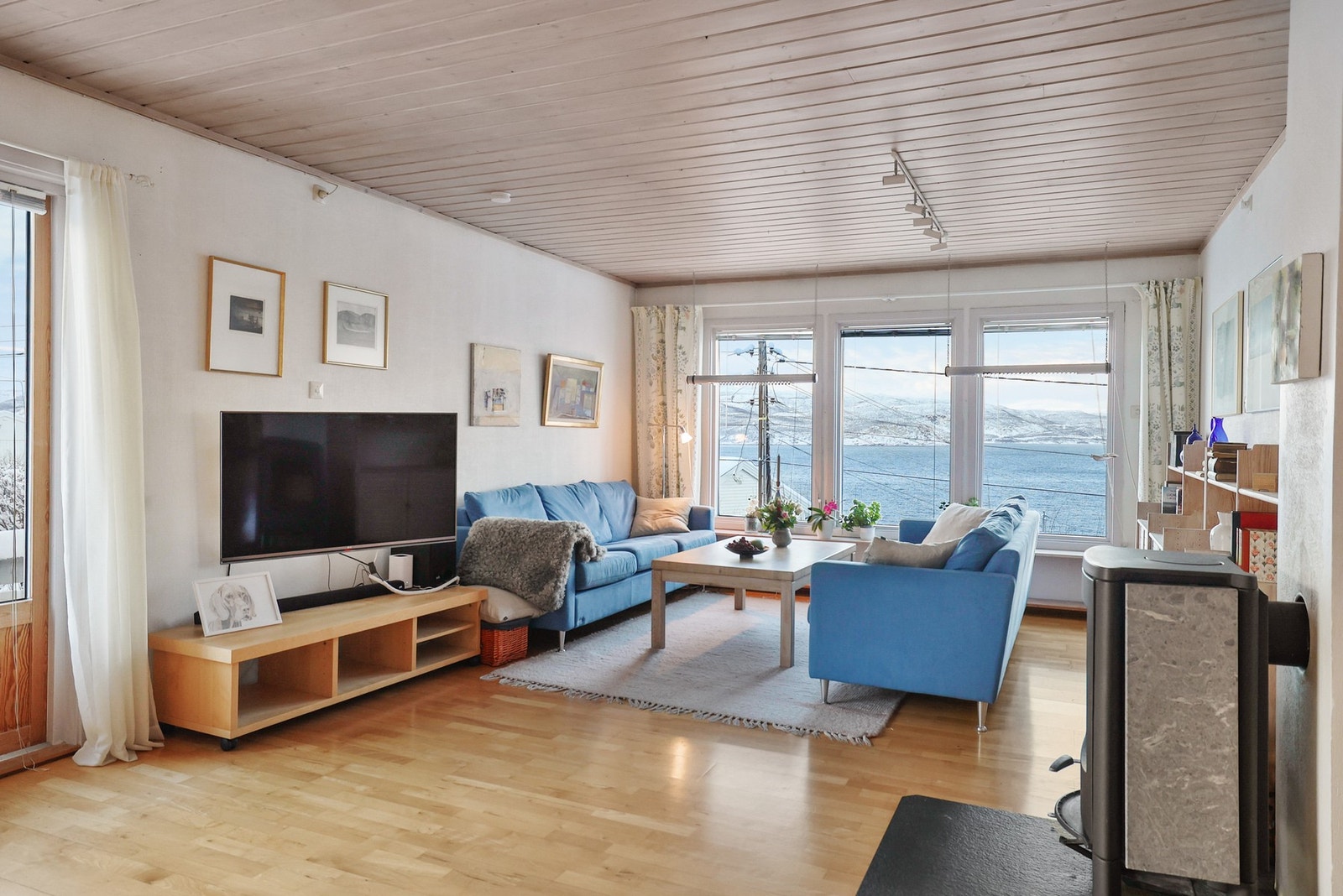 Boligen har en lys stue med store vindusflater. Galleribilde