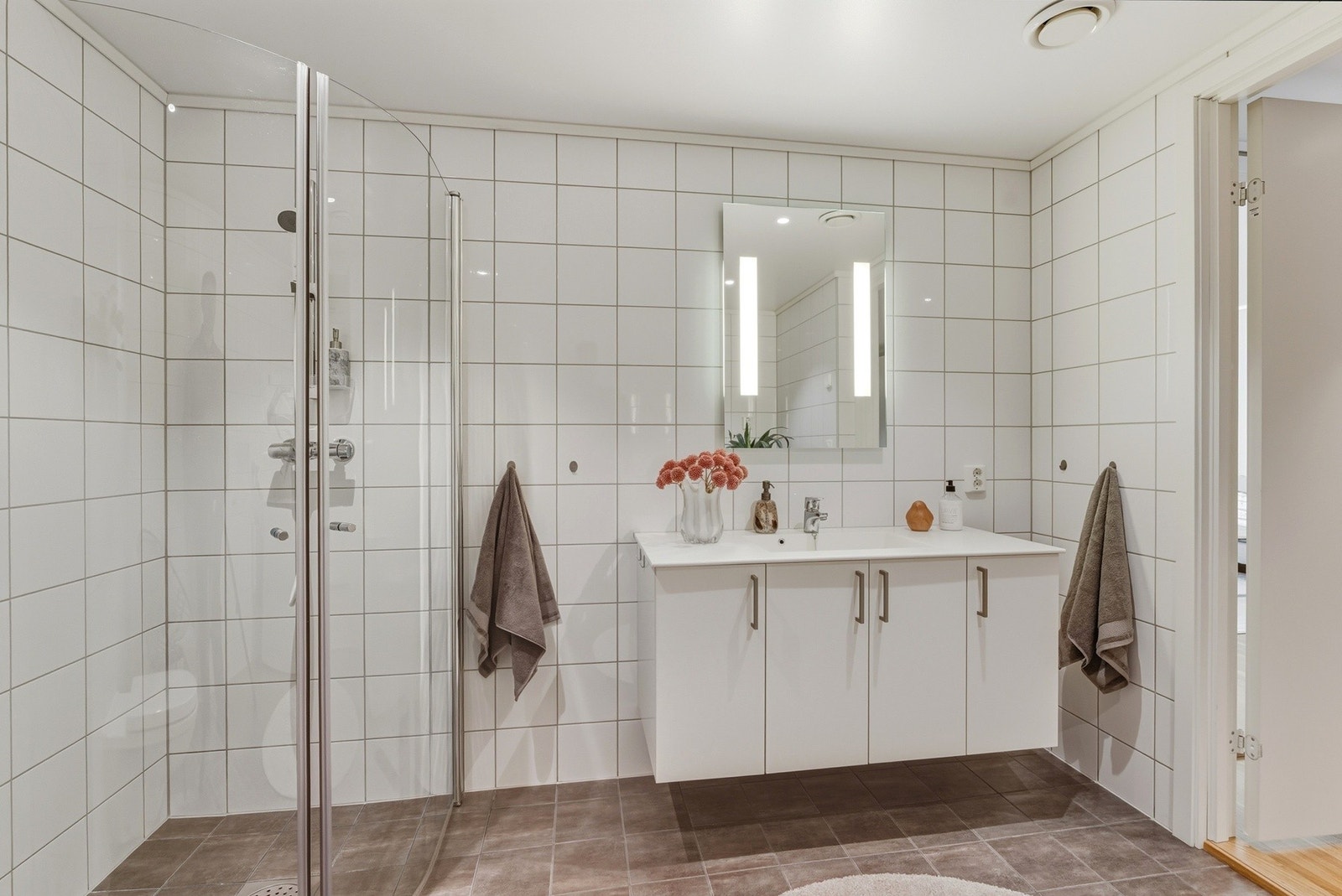 Badet har innredning med nedfelt servant, veggmontert toalett, dusjvegger/hjørne og opplegg for vaskemaskin. Galleribilde