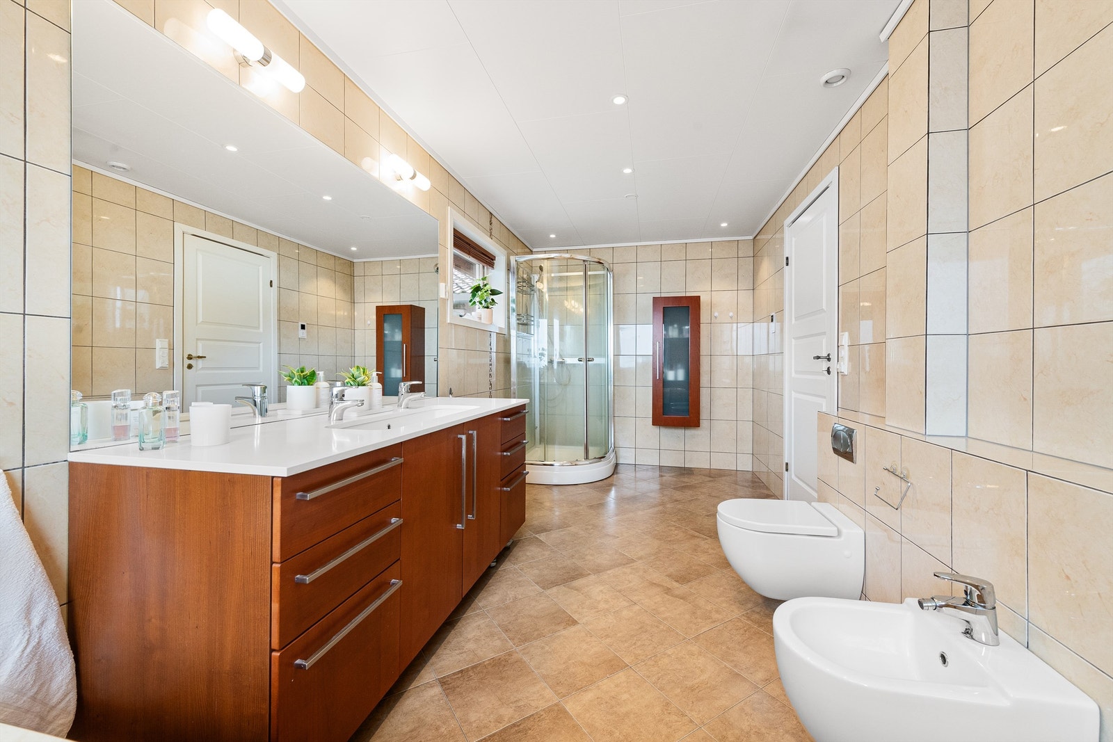 Badet har innebygd boblebadekar med badekarsarmatur, bide, dusjkabinett og vegghengt toalett. Galleribilde