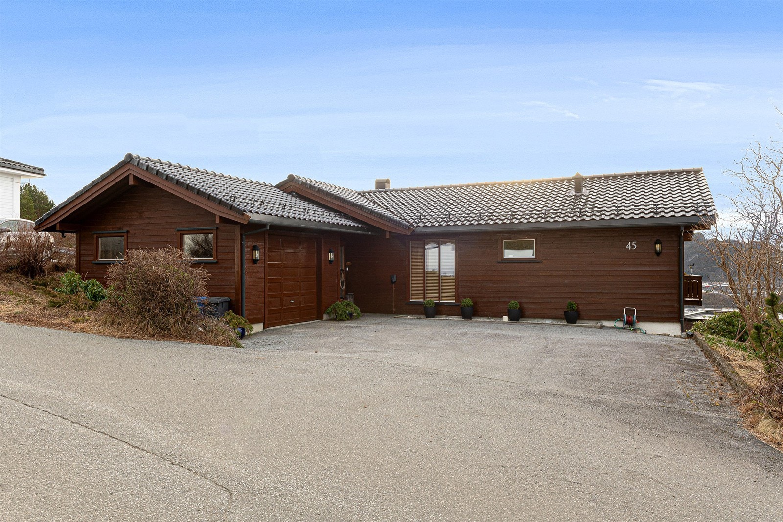 Fasade mot nord med asfaltert gårdsplass, garasje og inngangsparti Galleribilde