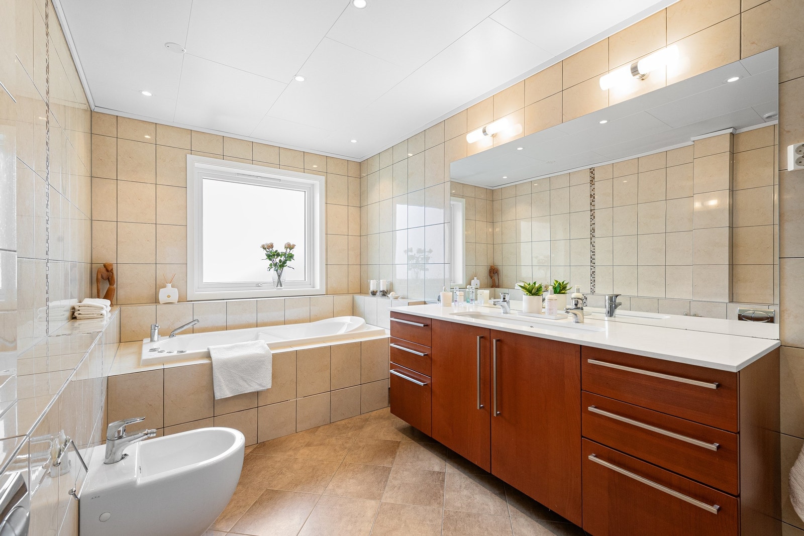 Baderomsinnredning fra Italian Design med dører og skuffer og ovenpåliggende servant med ett-greps armatur. Stort speil med overlys og stikkontakter over servant. Galleribilde