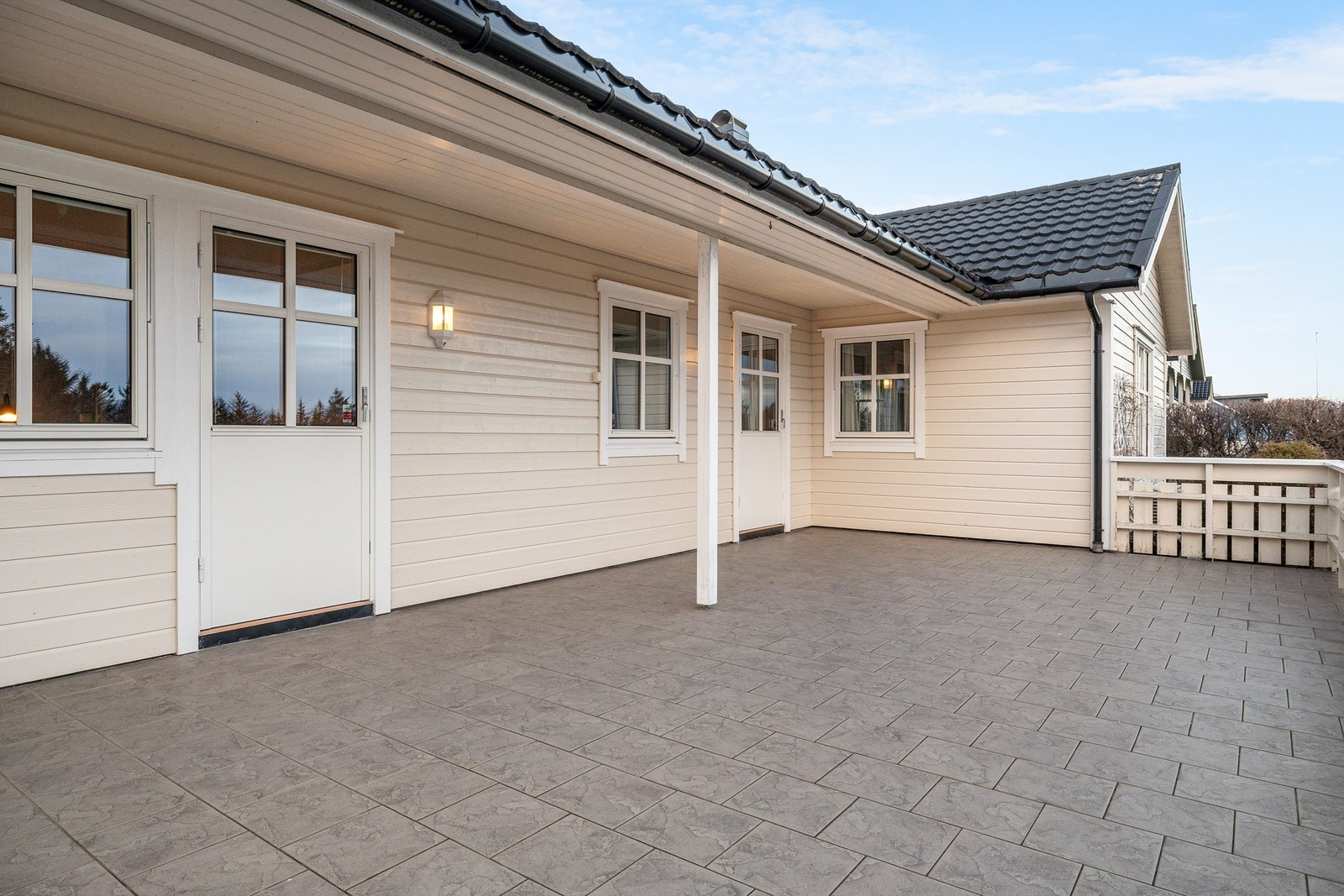 Stor terrasse på ca. 40 m² med flislagt dekke og delvis takoverbygg. Galleribilde